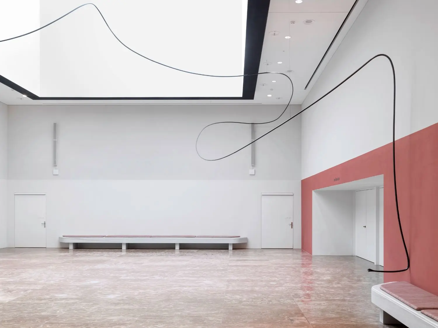 At first, you perceive it as a long curved line in the space, starting as an abstract squiggle wiggling across the otherwise immaculate architecture until you notice the snake heads with their almost cheeky expressions.